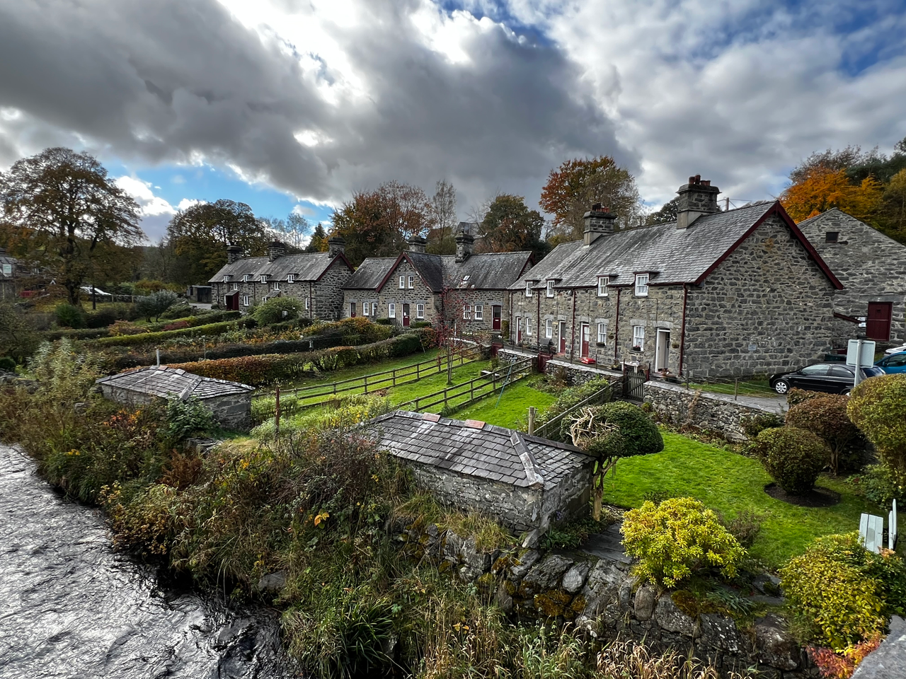 group of traditional stone buildings in wales set beside a river with gardens and landscaping